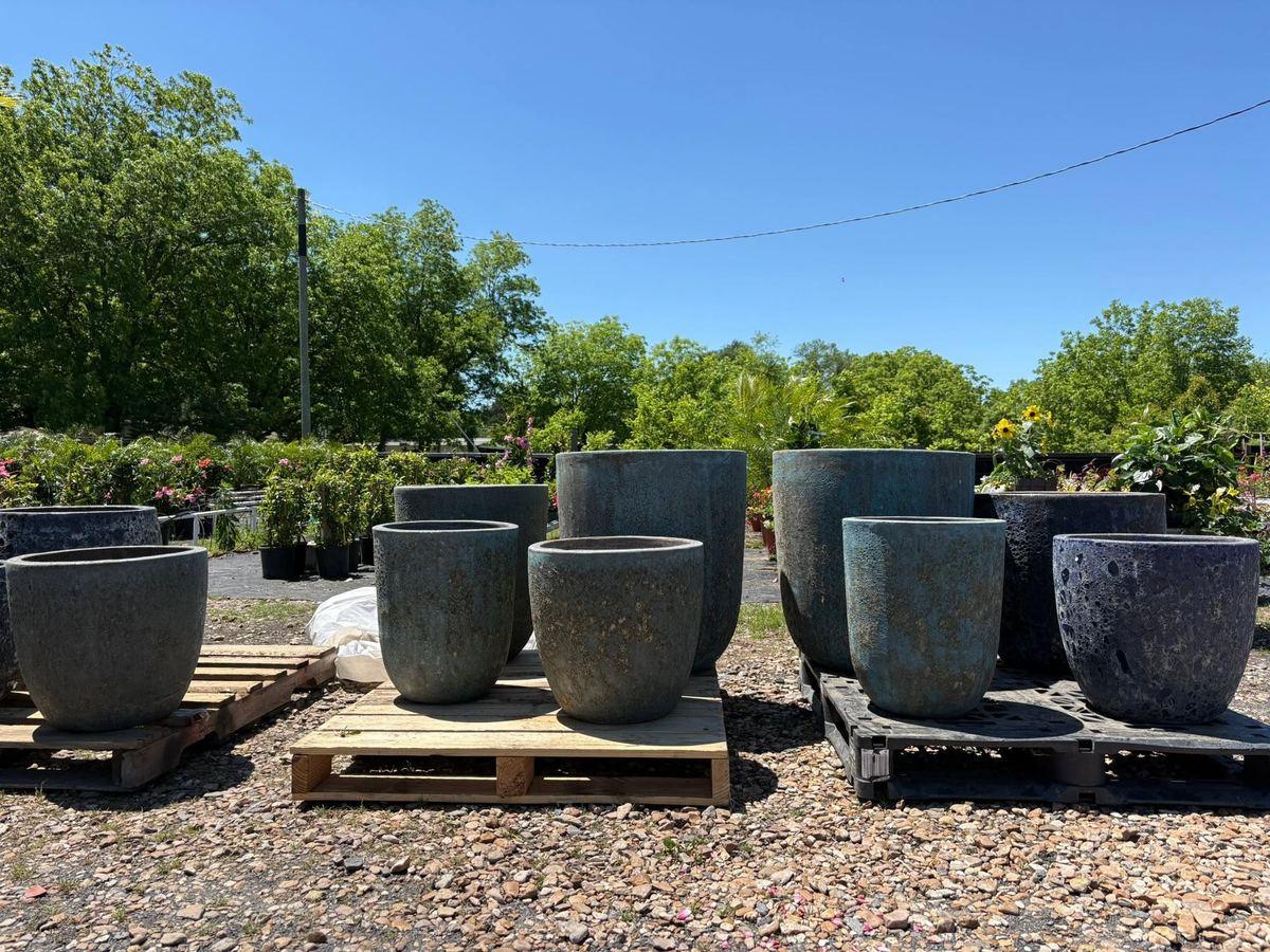 Rows of large glazed ceramic planters staged outdoors