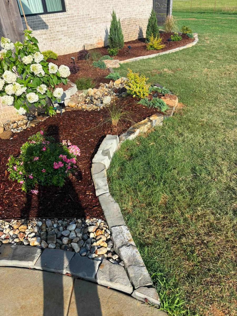 Stone-edged garden bed with a small rock water feature and hydrangeas