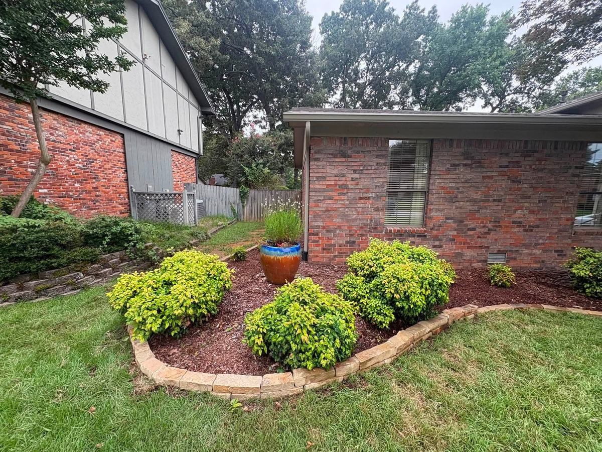 Golden shrubs and a glazed ceramic pot in a stone-edged bed