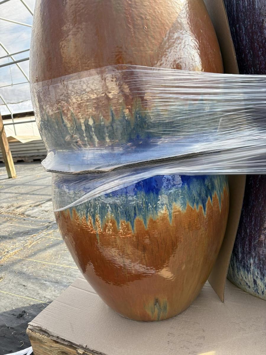 Large glazed ceramic pots wrapped for shipping in the greenhouse